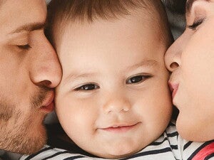 זוג הורים מנשק את הפעוט שלהם משני צידיו