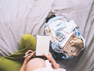 אמא בהריון אוחזת דף עם רשימת קניות לתינוק שיוולד