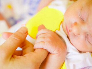 תינוק ישן מחזיק באצבעה של אימו
