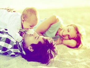 אבא ואמא שוכבים על חוף הים עם תינוקם