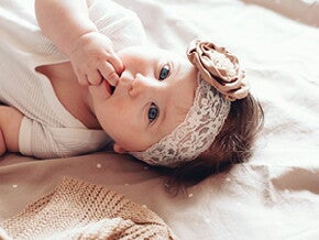 פעוטה שוכבת על גבה עם סרט לראשה