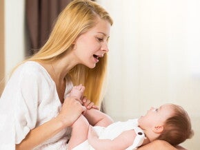 תינוק שוכב על רגליי אימו והיא מדברת אליו